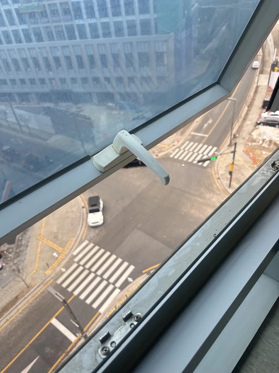 프로젝트 창문 손잡이가 고층에서 도심을 배경으로 젖혀진 채 헛도는 상태를 방문 확인하는 모습