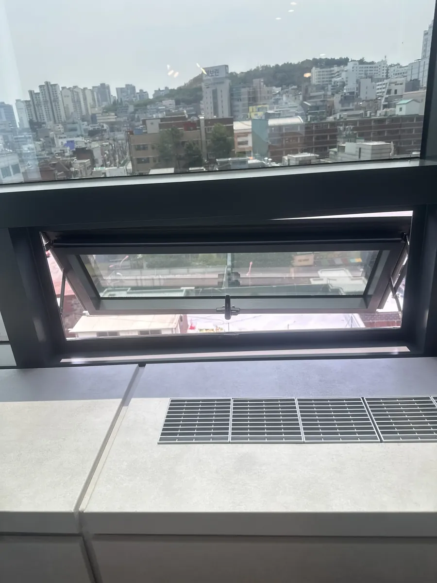 고층 사무공간 환기창이 완전히 닫히지 않고 살짝 열린 채 도심 전경이 보이는 방문 당시 모습